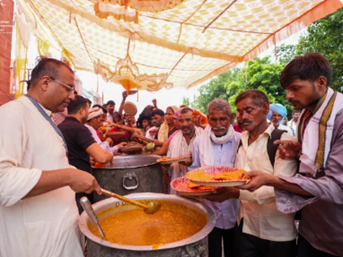 Devotees serving hot prasadam to pilgrims from large vessels at the temple